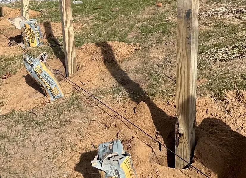 Traditional 4x4 wood fence post set in a concrete hole in the ground